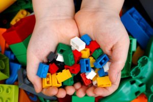 A CHILDS' HANDS HOLD UP A SELECTION OF DIFFERENTLY COLORED LEGO BLOCKS