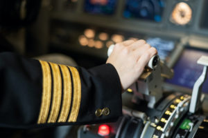 AN AIRPLANE PILOT'S HAND IS PLACED ON A PLANE ENGINE CONTROL STICK.