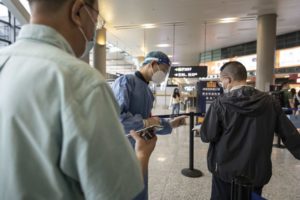 MASKED PASSENGERS AND OFFICIALS INTERACT IN A CHINESE AIPORT