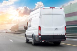 A DELIVERY VAN DRIVES DOWN AN URBAN ROAD