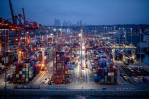 AN AERIAL VIEW CAN BE SEEN OF SHIPPING CONTAINERS AND CRANES AT THE PORT OF VANCOUVER.