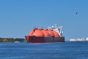 A LIQUIFIED NATURAL GAS TANKER FLOATS ON A BODY OF WATER DURING THE DAY.