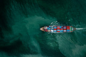 AN AERIAL VIEW OF A CONTAINERSHIP SAILING OVER MURKY WATERS.