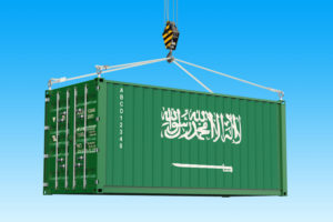 A CARGO CONTAINER BEARING THE SAUDI ARABIAN FLAG IS BEING HELD UP IN THE SKY BY A CRANE HOOK.