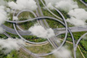 A COMPLEX SERIES OF ROADWAYS AND RAMPS, SEEN FROM HIGH ABOVE, IS PARTLY SHROUDED BY CLOUD
