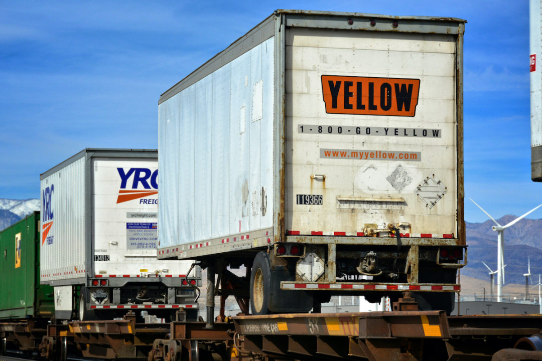 A YELLOW CORP TRAILER IS BEING TRANSPORTED BY A FREIGHT TRAIN.